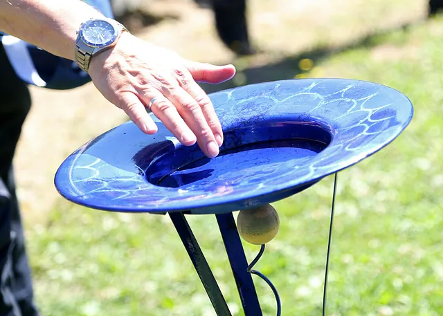 Hand berührt blaues Taufbecken im Freien.