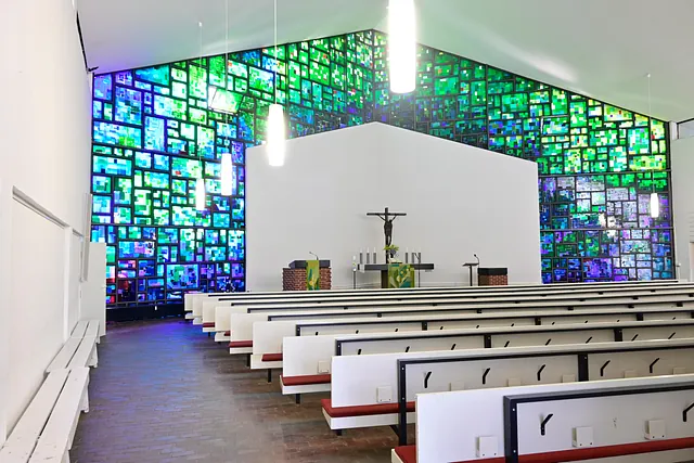 Contemporary church nave, altar, and colorful windows.