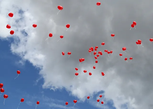 Rote Ballons steigen in bewölkten und blauen Himmel.