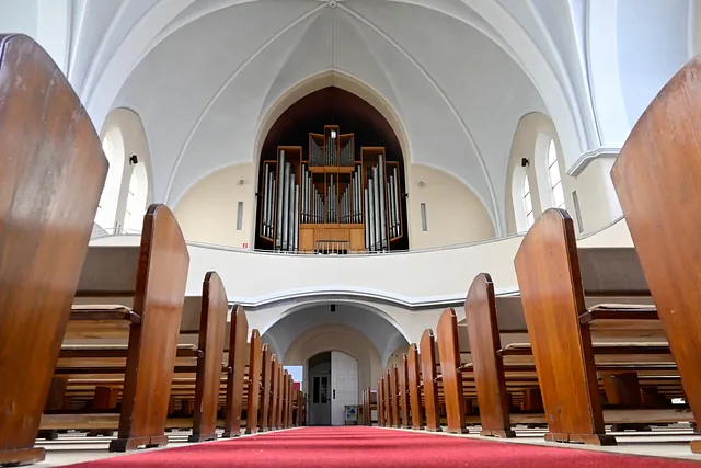 Leere Kirchenbänke blicken auf die große Pfeifenorgel.