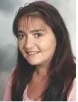Porträt einer lächelnden Frau mit dunklem Haar.