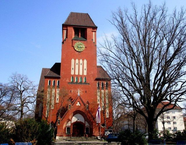 Historische Backsteinkirche mit hohem Uhrturm.