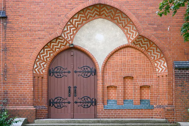 Verzierte Holzkirchentür in Backsteinbogen.