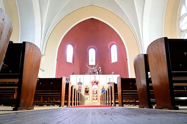 Kircheninneres mit Bänken, Altar und Fresken.