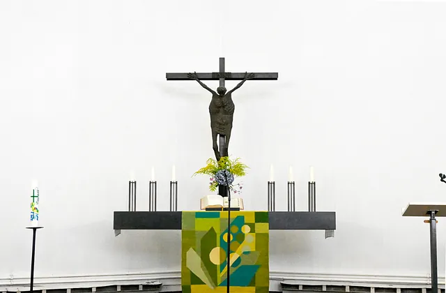 Kruzifix und Kerzen auf minimalistischem Kirchenaltar.