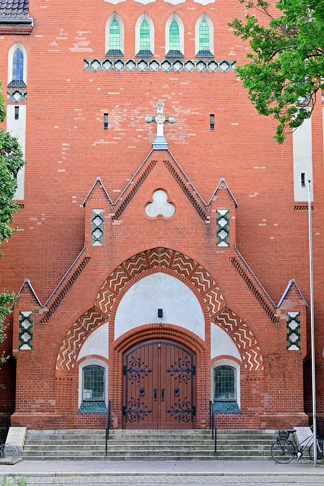 Verzierte Backsteinkirchenfassade mit großer Holztür.