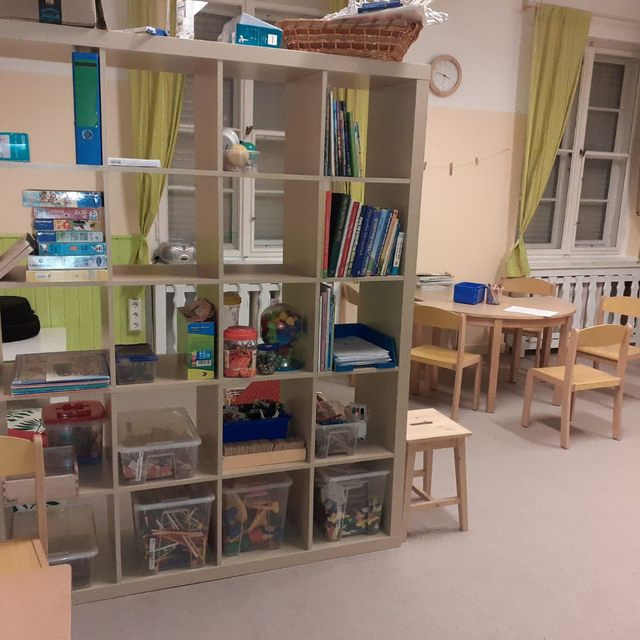 Kinderaktivitätsraum mit großem Regal und kleinen Tischen.