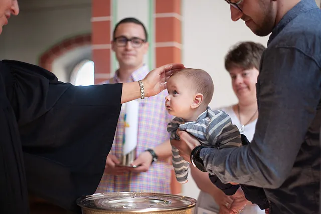 Baby wird vom Pfarrer in der Kirche getauft.