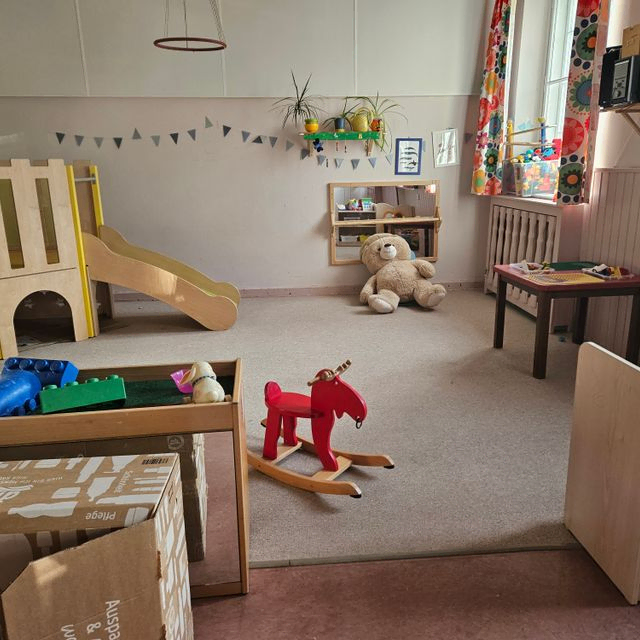 Kinderspielzimmer mit Rutsche, Schaukelpferd und Teddybär.