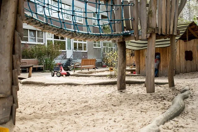 Kirchlicher Spielplatz im Freien mit Holzstrukturen und Sand.